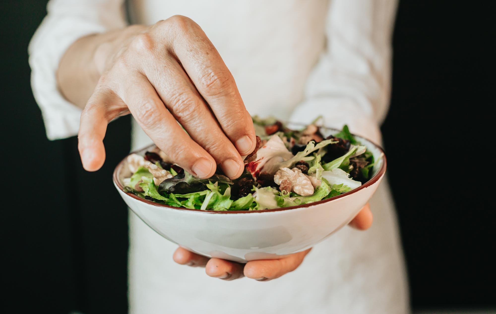 close-up of chef's hands plating a salad